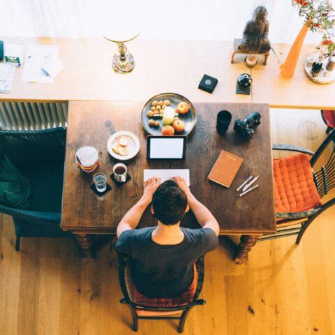 man sitting at desk while typing on keyboard using an ipad